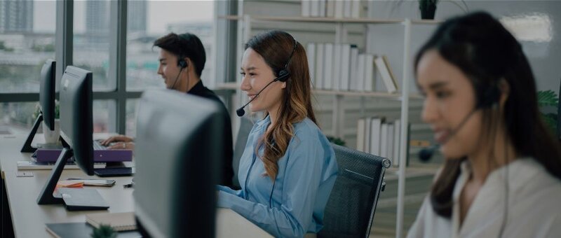 Mehrere Personen mit Headphones bedienen PCs 
